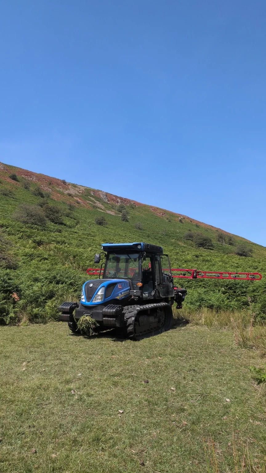 Tracked tractor with boom on hillside